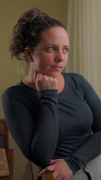 Contemplative white woman resting chin on knuckles while gazing pensively indoors reflecting on deep memories personal choices and quiet mindfulness