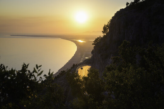 View of Rana e hedhun beach and the coastal road winding along the cliffs at sunset in Shengjin, Lezhe County, Albania.