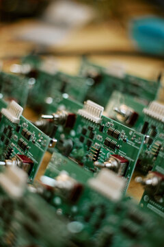 Vertical shot of electronic green circuit boards with switches arranged in production line. Hardware components ready for computer engineering, manufacturing and technology concept