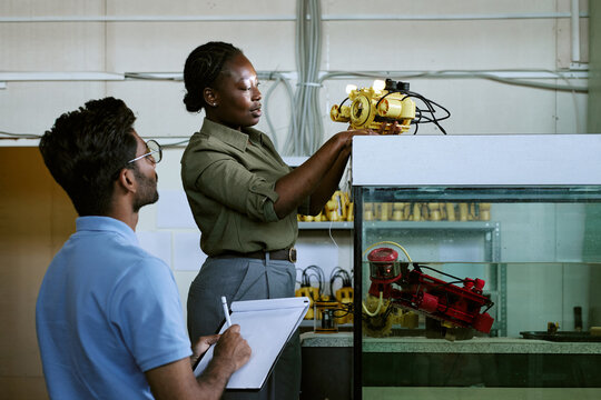 African American young woman and multiethnic young man testing robotic underwater drone in laboratory. Useful for engineering education and STEM research campaigns