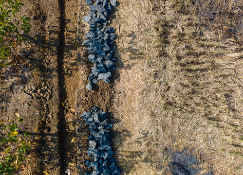 Aerial View of Pile of Split Rocks in an After-Harvest Agricultural Field. The Isolated Rock Contrasts with the Open Rural Farmland, Creating a Distinctive Agricultural Landscape Viewed from Above.