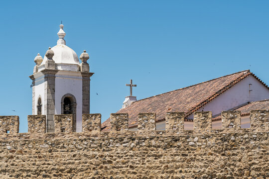 View of the historic stone castle walls and the bell tower of the church in Sines, Setubal, Portugal.