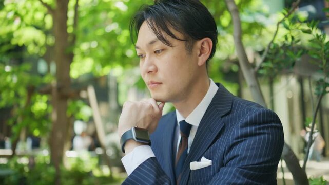 Japanese businessman lost in thought while working outdoors