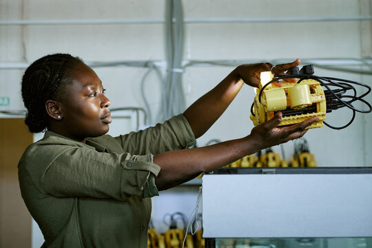 Young African American woman engineer inspecting underwater robotic device in laboratory. Concept representing robotics research, useful for engineering education and STEM campaigns