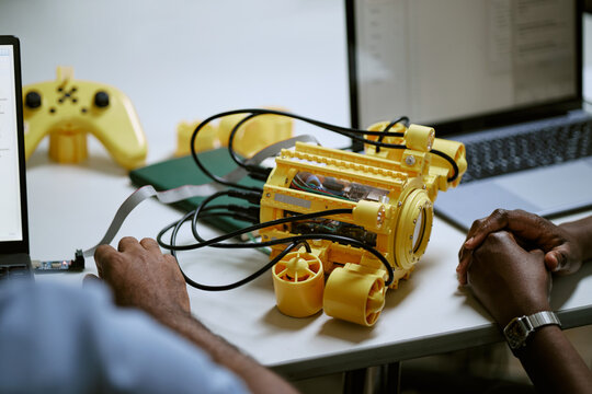 African American young adults testing DIY underwater robotics drone beside laptops during engineering workshop. Visual suitable for STEM education and technology innovation campaigns