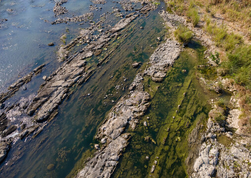 Aerial View of Rugged Rock Formations with Vegetation Sprouting on and Around the Rocks in a Clear Turquoise River During Morning in Wangon, Central Java, Indonesia. 