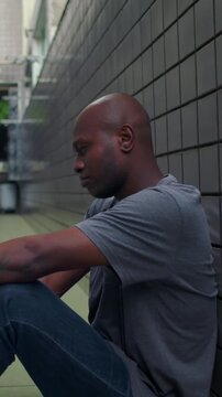 Exhausted African American individual resting back against residential corridor wall experiencing deep emotional numbness quiet decompression and post-crisis fatigue