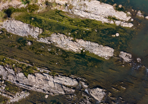 Aerial View of Rugged Rock Formations with Vegetation Sprouting on and Around the Rocks in a Clear Turquoise River During Morning in Wangon, Central Java, Indonesia. 