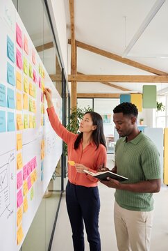 Colleagues updating a kanban board with sticky notes