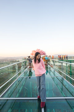 Asian female tourist walking on the transparent glass skywalk at Wat Phra That Pha Ngao in Chiang Rai.