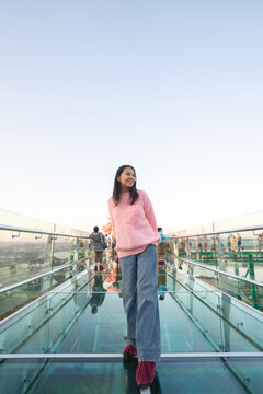 Asian female tourist walking on the transparent glass skywalk at Wat Phra That Pha Ngao in Chiang Rai.