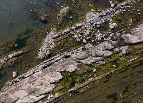 Aerial View of Rugged Rock Formations with Vegetation Sprouting on and Around the Rocks in a Clear Turquoise River During Morning in Wangon, Central Java, Indonesia. 