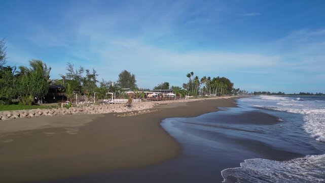 Meulaboh, Indonesia : Forward aerial drone footage of wave breaks into beach by small stalls in Meulaboh, coastal town in Aceh province of Sumatera in Indonesia.