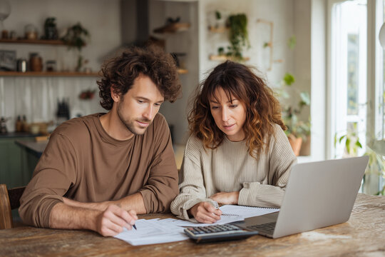 Focused Couple Managing Family Budget And Financial Charts On Laptop At Home