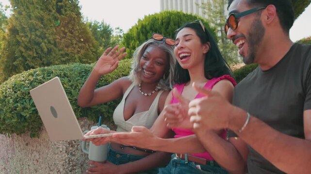 Diverse young professionals video calling with a laptop outdoors