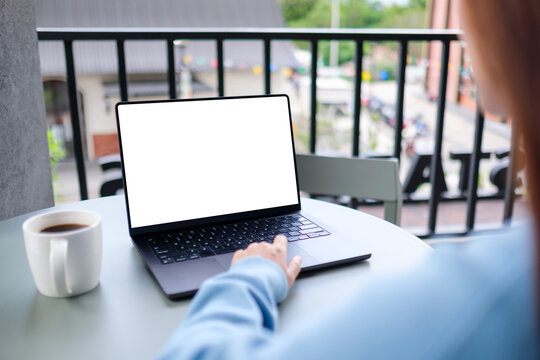 Mockup image of a woman working on laptop computer with blank white desktop screen in cafe