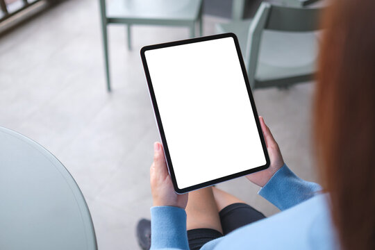 Mockup image of a woman holding digital tablet with blank white desktop screen in cafe