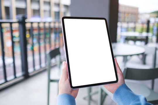 Mockup image of a woman holding digital tablet with blank white desktop screen in cafe