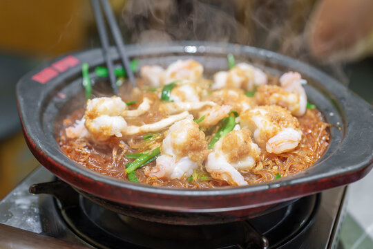 Woman tourist eating baked shrimp with glass noodles and garlic in restaurant. Popular foods for tourist eating in Chengdu, China. Chinese Asia and Sichuan foods concept