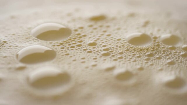 Creamy foam bubbles ripple across an abstract liquid surface in macro view. Cosmetic advertising, skincare campaigns, and bath and spa design.