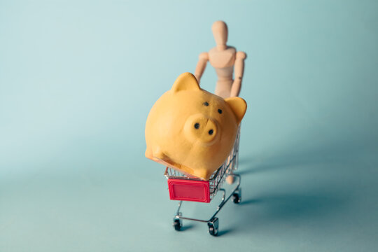 Piggy bank in shopping cart on blue background. Concept of saving money.
