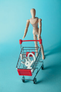 Wooden mannequin with shopping cart and 50 percent discount on blue background