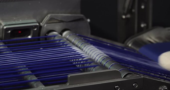 White flatbread moves along blue conveyor toward baking equipment. Automated bakery line transports shaped dough pieces for controlled thermal processing