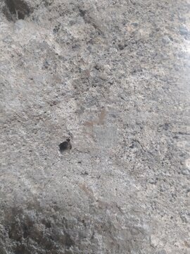 Semarang, Central Java, Indonesia - September 15 2026: Close up of rough grey concrete wall texture with small hole and stone surface detail