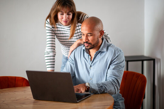Couple reviewing online information together on laptop at home