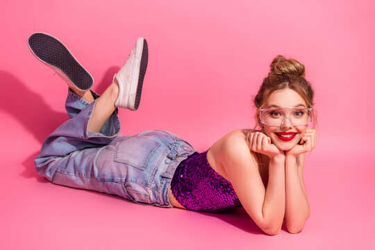 Playful young woman in trendy casual disco fashion on pink summer background exuding happiness and charm