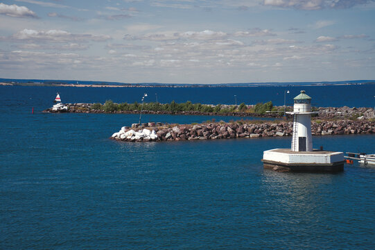 White Lighthouse in Harbor Entrance in Sunny Weather on the Coast.