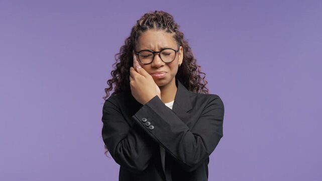 Pretty school-girl holding cheek with painful expression. College student woman suffering from toothache, dental sensitivity, oral health problems and discomfort.