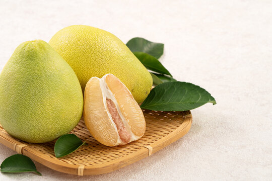 Fresh pomelo fruit with leaf on white table background.