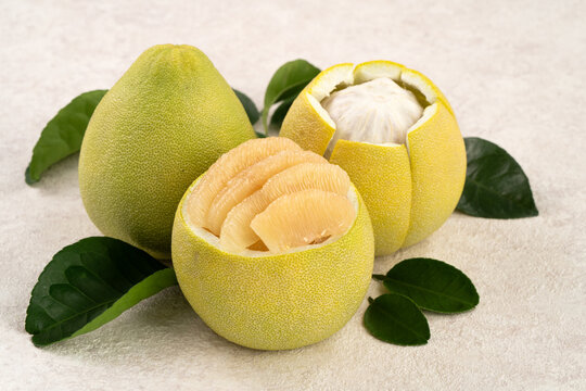 Fresh pomelo fruit with leaf on white table background.