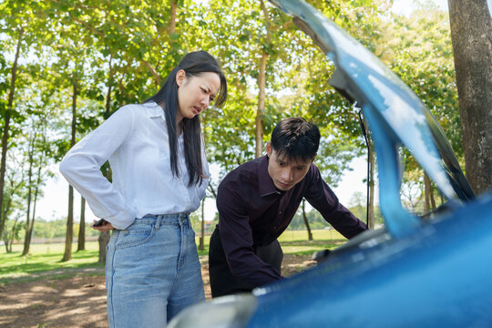 Asian woman and mechanic inspecting broken car engine outdoors for insurance claim