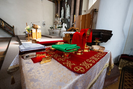 Altar with chalice, paten and folded vestments on red altar cloth ready for Catholic Mass in a historic church interior