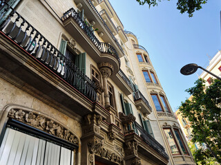 Elegant historic residential building with ornate balconies and shutters in Barcelona, Spain under a clear blue sky © AS Photo Family