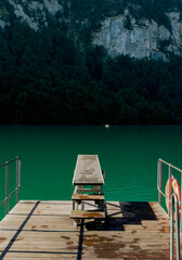 Fototapeta premium Diving board and life buoy on a dock over a green alpine lake
