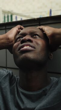 Agonized African American individual clasping temples while tilting gaze toward ceiling in dark passage experiencing acute dread desperation and urgent plea