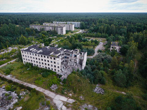 Aerial view of the abandoned Soviet military town of Irbene with decaying concrete apartment buildings surrounded by overgrown forest and rural landscape in Irbene, Ventspils Municipality, Latvia.