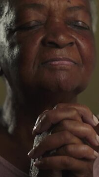 Reverent elderly African American matriarch with closed eyes and clasped hands immersed in silent prayer radiating steadfast faith and gratitude