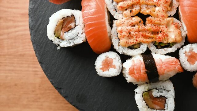 Assorted sushi platter slowly rotating to showcase colorful maki rolls, nigiri and fresh Japanese food arranged on a serving tray.