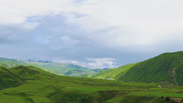 Rolling Green Hills and Valley Under a Cloudy Sky