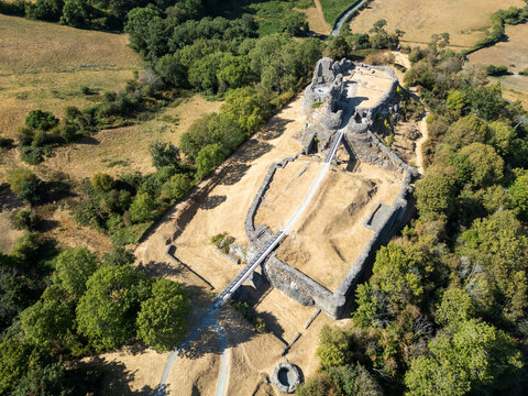 Aerial view of Montgomery Castle ruins surrounded by lush green trees and dry grassy fields in Montgomery, Powys Wales, United Kingdom.