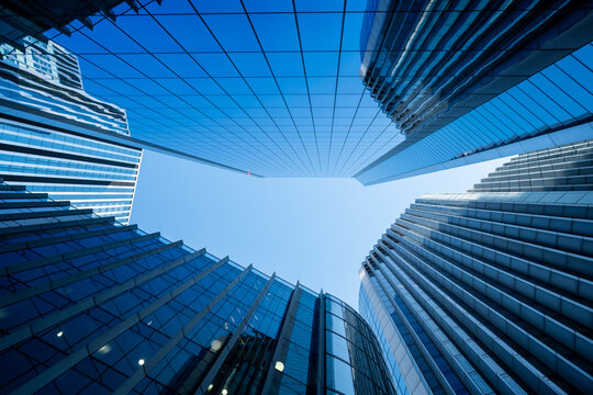 Low angle view of modern glass towers in London England creates a dramatic urban canyon with blue sky geometry and contemporary architecture