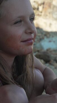 Charming young girl resting outdoors with watermelon juice on her face, portrait shot capturing innocent summer moments.