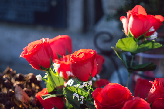 Close-up of bright red artificial roses placed as a memorial tribute in a Romanian cemetery
