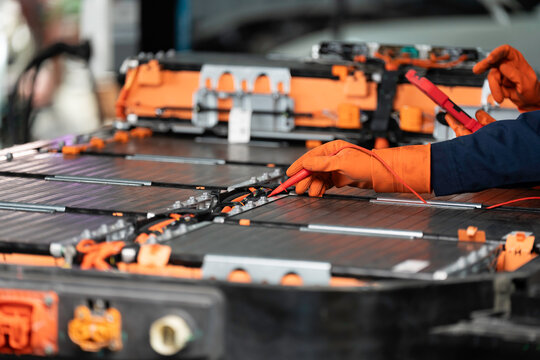 High-voltage battery checks, maintenance. Technician or Mechanic wearing protective gloves diagnosing electric car vehicles battery, Electric car battery replacement