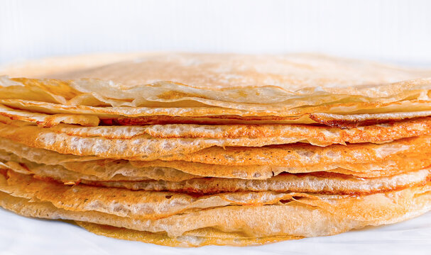 Close-up of a fresh stack of traditional thin pancakes. Selective focus on texturized pancake edge. Minimalist food photography