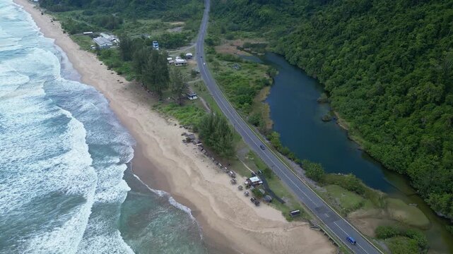Aceh, Indonesia : Aerial drone footage of coastline near Banda Aceh of Sumatera, Indonesia. With orbit motion showing wave breaks into the beach, cars on coastal road, and lake by rainforest